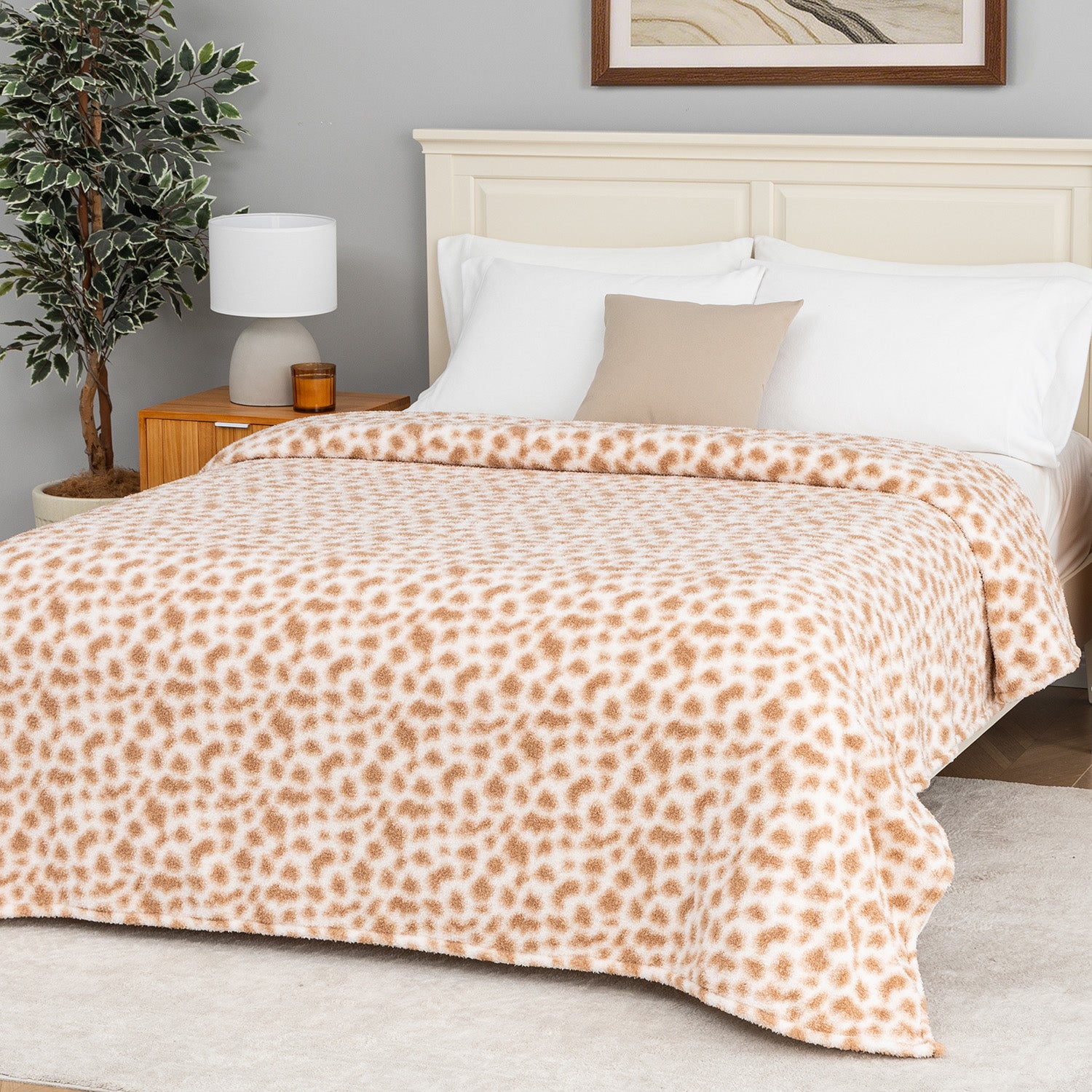 Bedroom with a bed covered in a leopard print blanket, nightstand, and lamp.