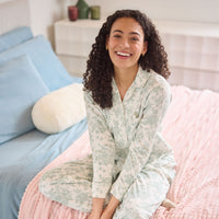 A model sitting and smiling on a cozy colorful bed.