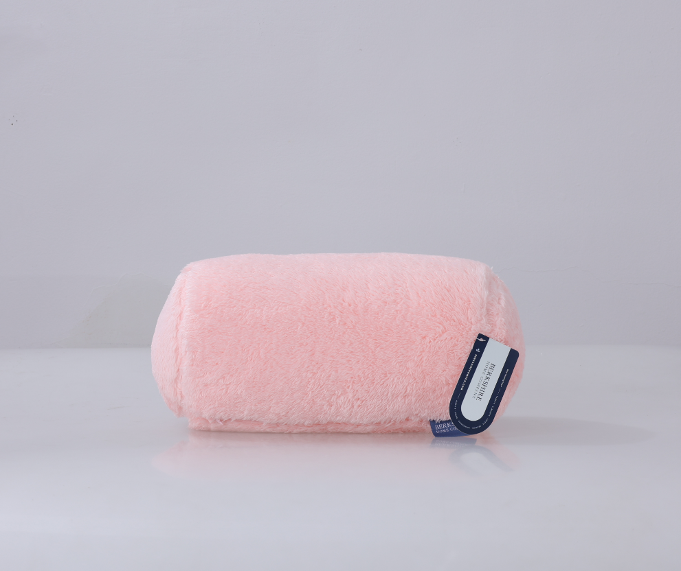 Pink cylindrical pillow with a label on a light gray background