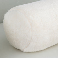 Close-up of a white fluffy cushion on a light gray surface.