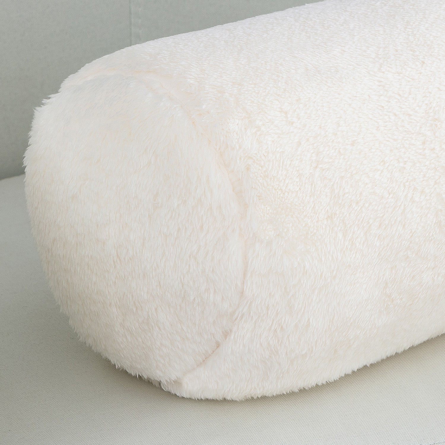 Close-up of a white fluffy cushion on a light gray surface.