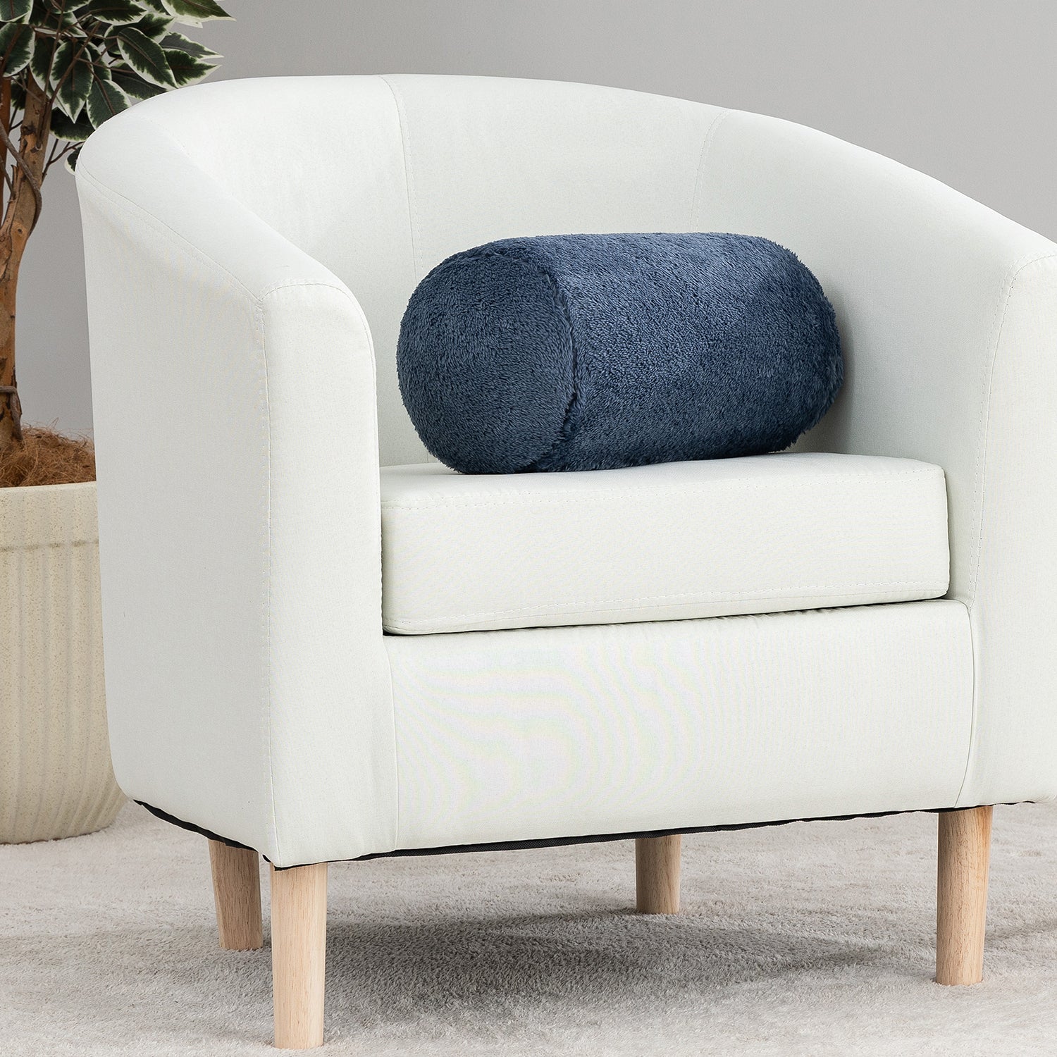 White armchair with a blue cylindrical pillow on a neutral background