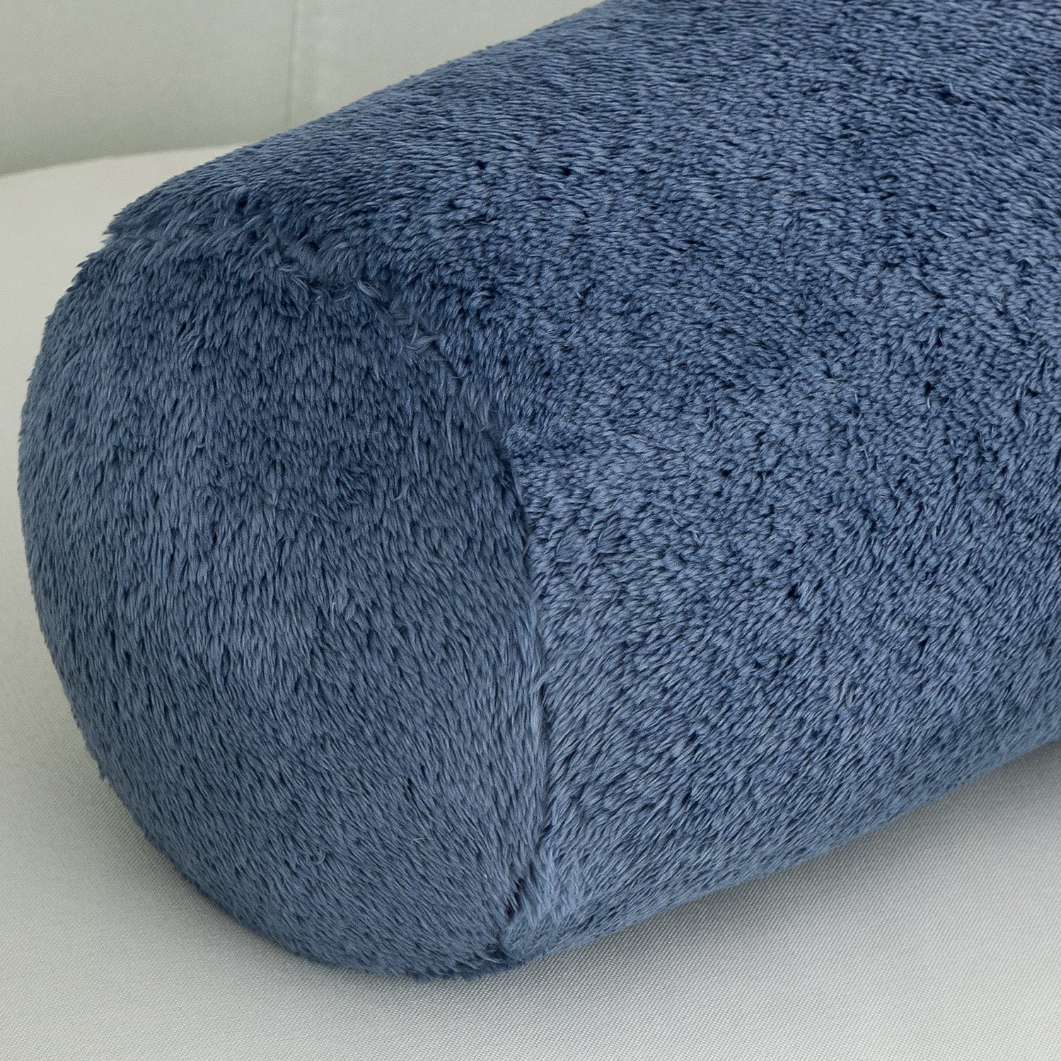 Blue textured cylindrical pillow on a light gray background
