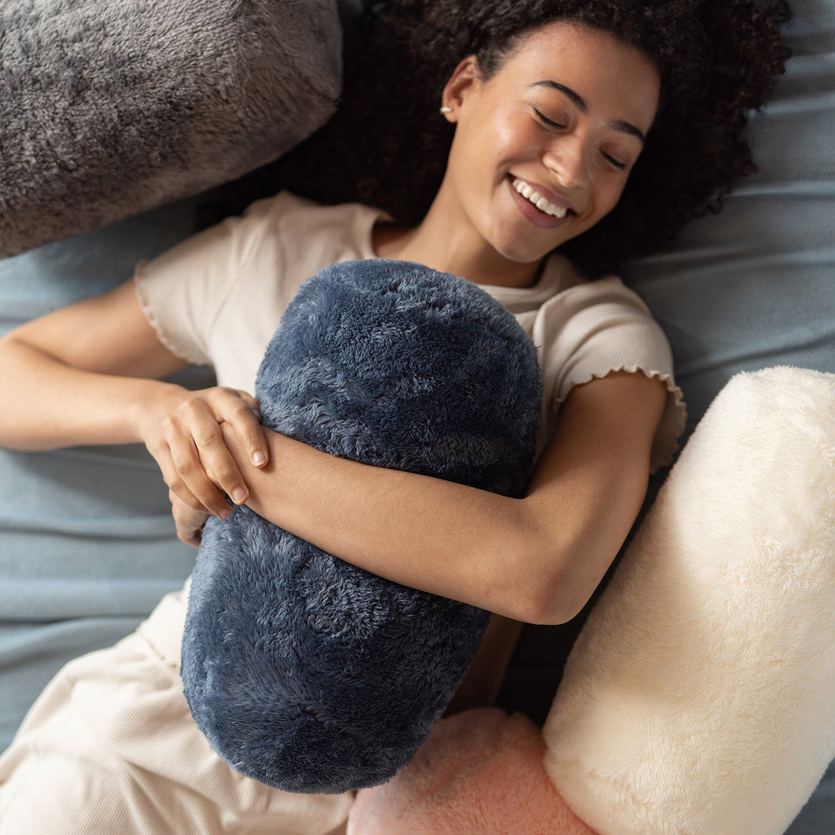 Woman lying on a bed holding a blue plush pillow