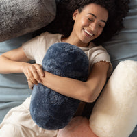 Woman lying on a bed holding a blue plush pillow