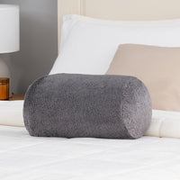 Gray fluffy pillow on a bed with white and beige pillows in the background.