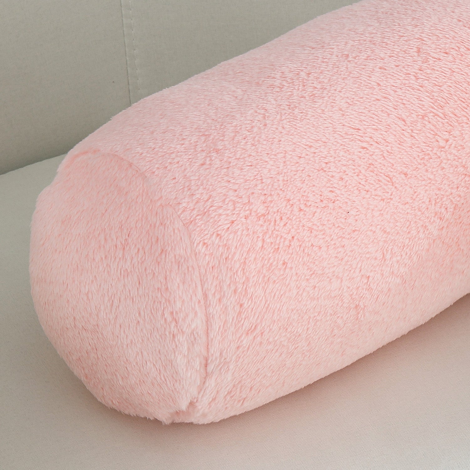Pink cylindrical pillow on a light gray surface