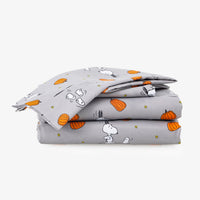 A stack of three folded gray fabric items, likely bedding or blankets, printed with a cartoon dog and pumpkin pattern, set against a plain light gray background.