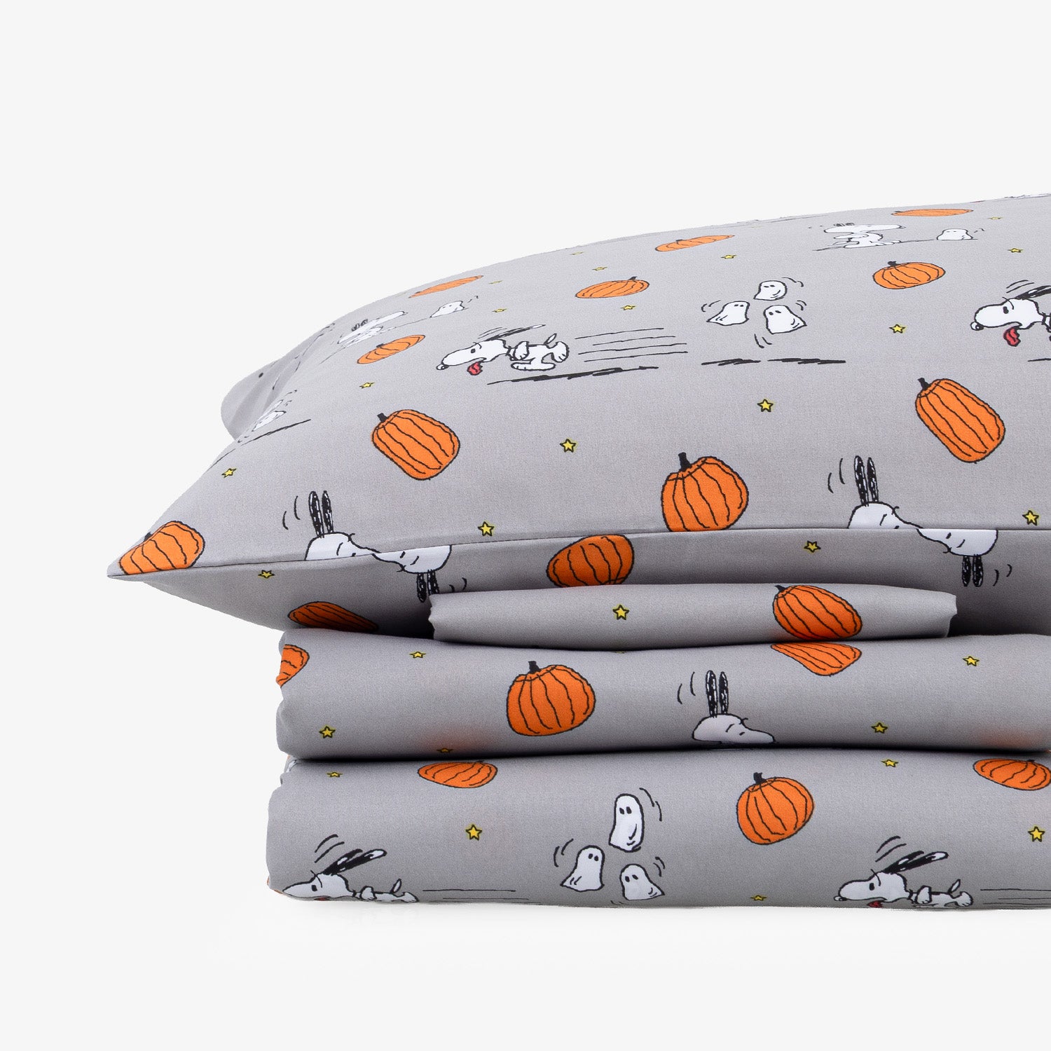 A stack of gray bedding, including a pillowcase and folded sheets, printed with an orange pumpkin and white cartoon dog pattern on a light gray background.