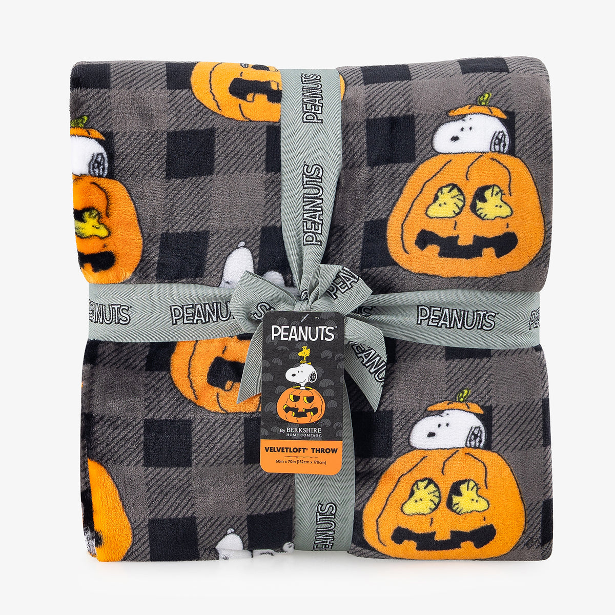 A folded plush blanket featuring a Halloween theme with a black and gray buffalo plaid background, orange pumpkins, and Snoopy and Peanuts characters, tied with a gray ribbon printed with 'PEANUTS'.