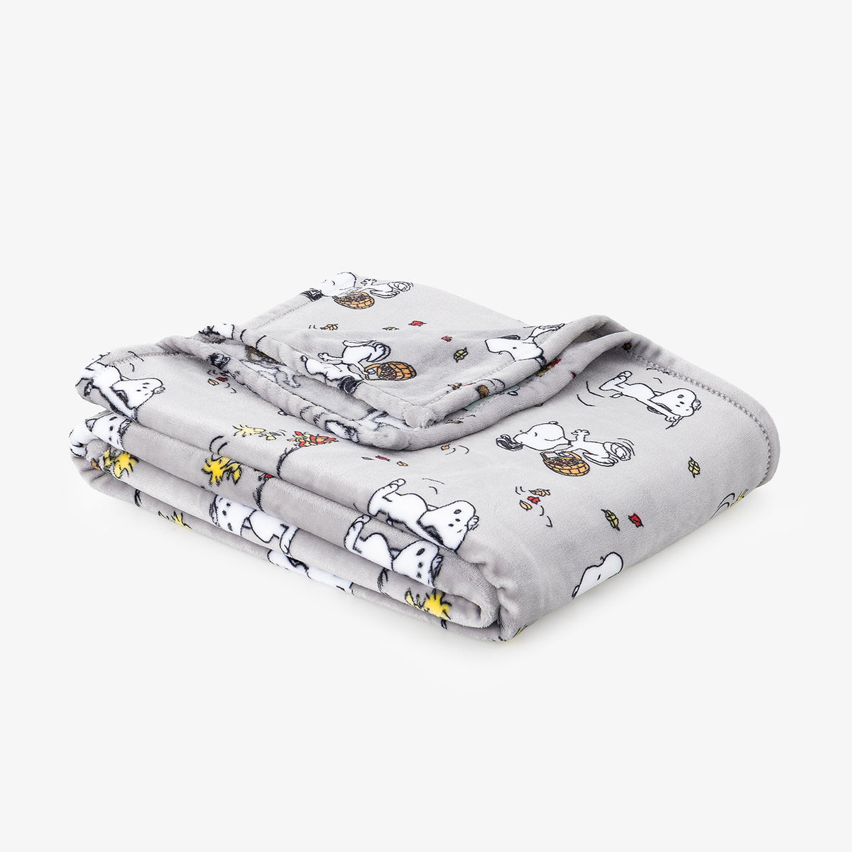 A folded light gray blanket featuring a cartoon print of Snoopy and Woodstock, shown on a clean white background.