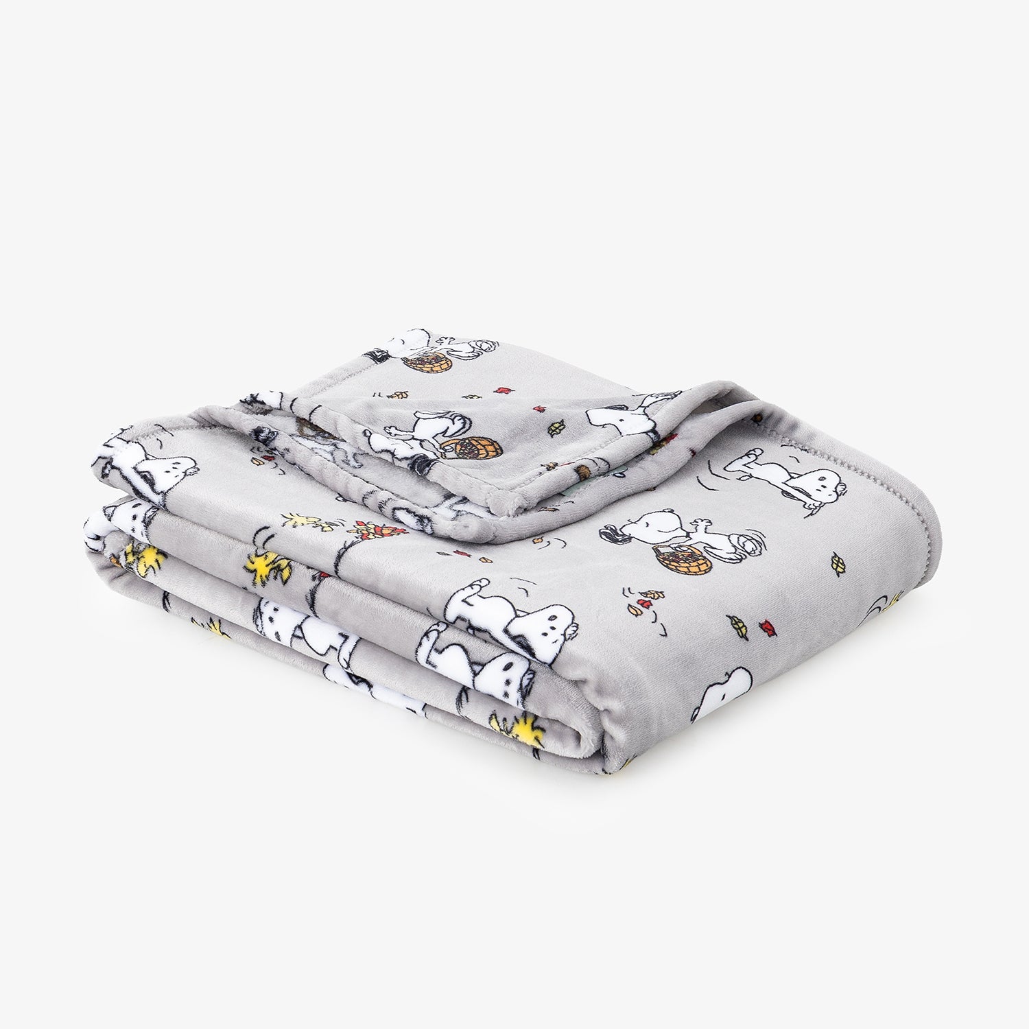A folded light gray blanket featuring a cartoon print of Snoopy and Woodstock, shown on a clean white background.