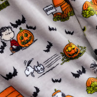 Close-up of a white fabric printed with Peanuts Halloween characters, including Snoopy, Woodstock, a pumpkin, bats, and Boo, with a soft plush texture.
