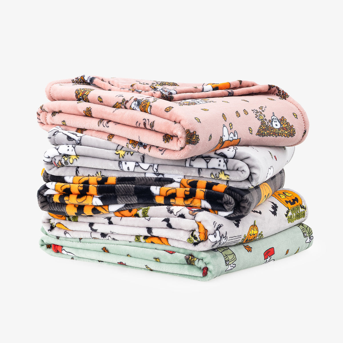 A stack of four folded plush blankets with cartoon animal prints in pink, gray, black, orange, and mint green, set against a plain light gray background.