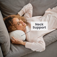 A woman laying on a neckroll pillow displaying neck support functionality.