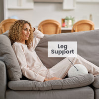 A woman laying with a neckroll pillow under her legs displaying leg support functionality.