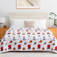 A white bedding set, including a comforter and matching pillow shams, featuring a repeating cartoon pattern of Snoopy and his doghouse, pumpkins, and leaves. The bed is styled in a bright, modern bedroom with a light wood headboard, bedside tables, and a framed picture on the wall.