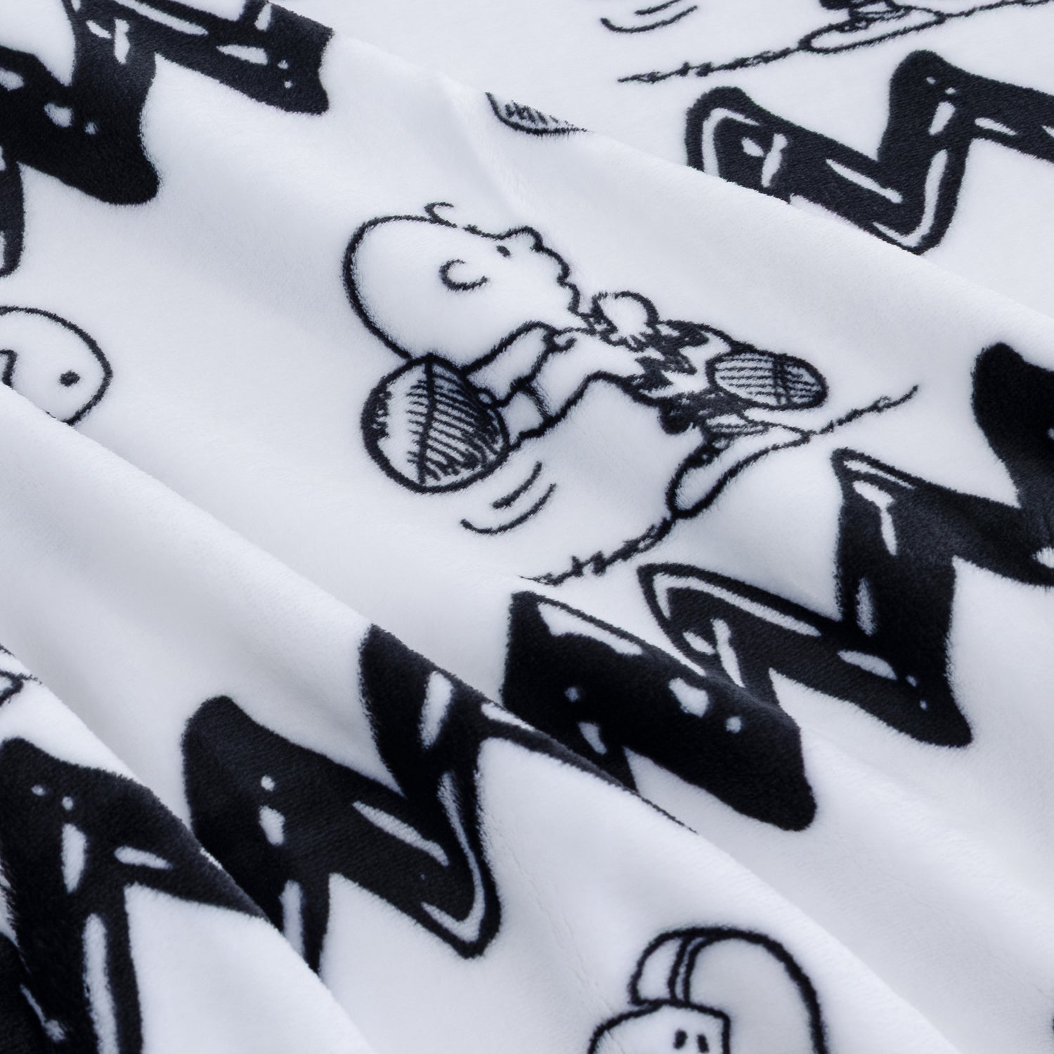 Close-up of a white fabric with a black cartoon print featuring Snoopy and a zigzag pattern.