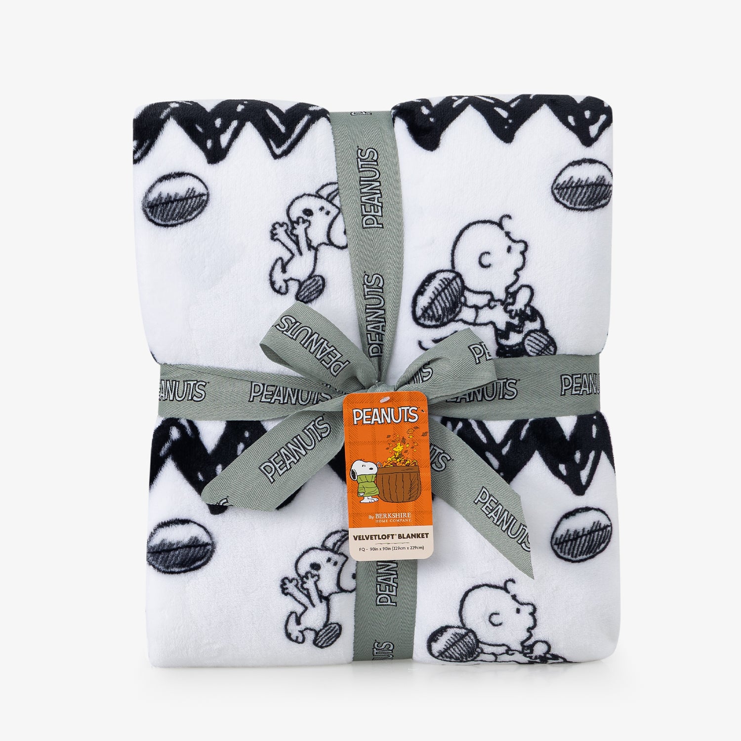 A white blanket with a black Snoopy and Woodstock pattern and zigzag border folded neatly on a white surface.