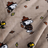 Close up of a tan peanuts printed blanket featuring snoopy in a jacket.