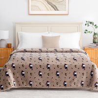 A tan printed Peanuts blanket draped over a bed in a bright bedroom.