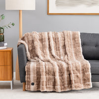A orange and brown striped and textured faux fur heated throw draped over a sofa.