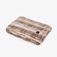 A folded electric heated blanket with a plush faux fur texture in shades of taupe and beige, featuring a small black control panel on the side, set against a plain white background.