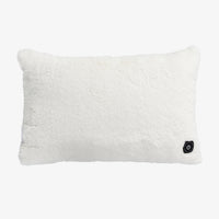 A rectangular white faux fur throw pillow with a small black power button on the bottom right corner, shown against a plain white background.