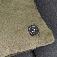 Close-up of a plush, textured electric heated throw pillow in olive green, featuring a black square control button with a power symbol on the corner, resting on a dark gray fabric surface.