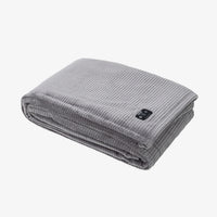 A folded gray ribbed corduroy blanket with a small black brand tag, shown on a clean white background.
