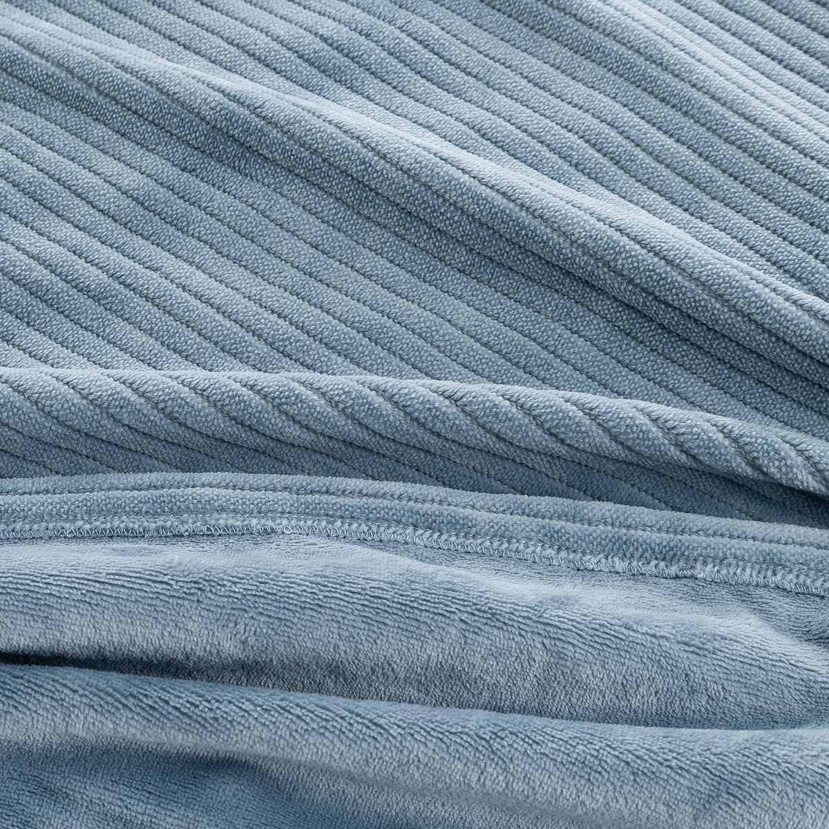 A close-up of a dusty blue ribbed fabric, showing the textured corduroy-like vertical ridges and soft plush terry-like lower section.