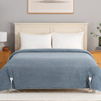 A bed dressed in a textured slate blue striped duvet cover with white pillows, set in a styled bedroom with a cream headboard, wooden side tables, and a gray wall.