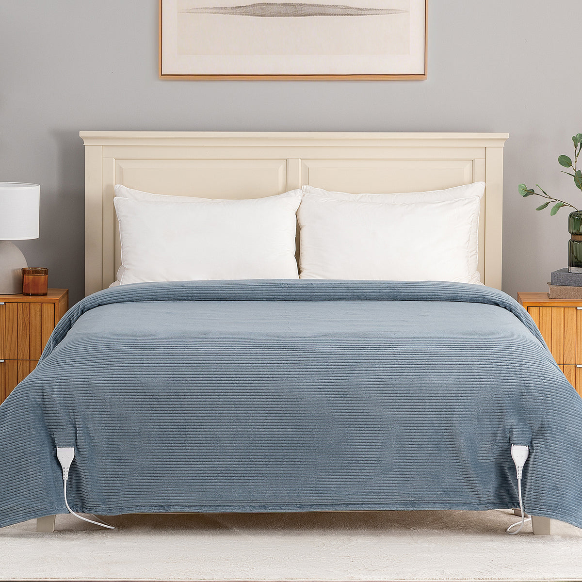 A bed dressed in a textured slate blue striped duvet cover with white pillows, set in a styled bedroom with a cream headboard, wooden side tables, and a gray wall.