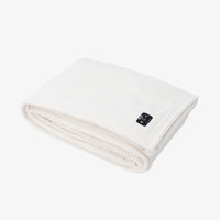 A folded white textured blanket with a small black control panel on the corner, set against a plain white background.