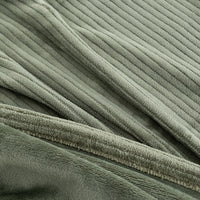Close-up of a ribbed, plush fabric in a muted sage green color, showing the soft texture and folded drapery.
