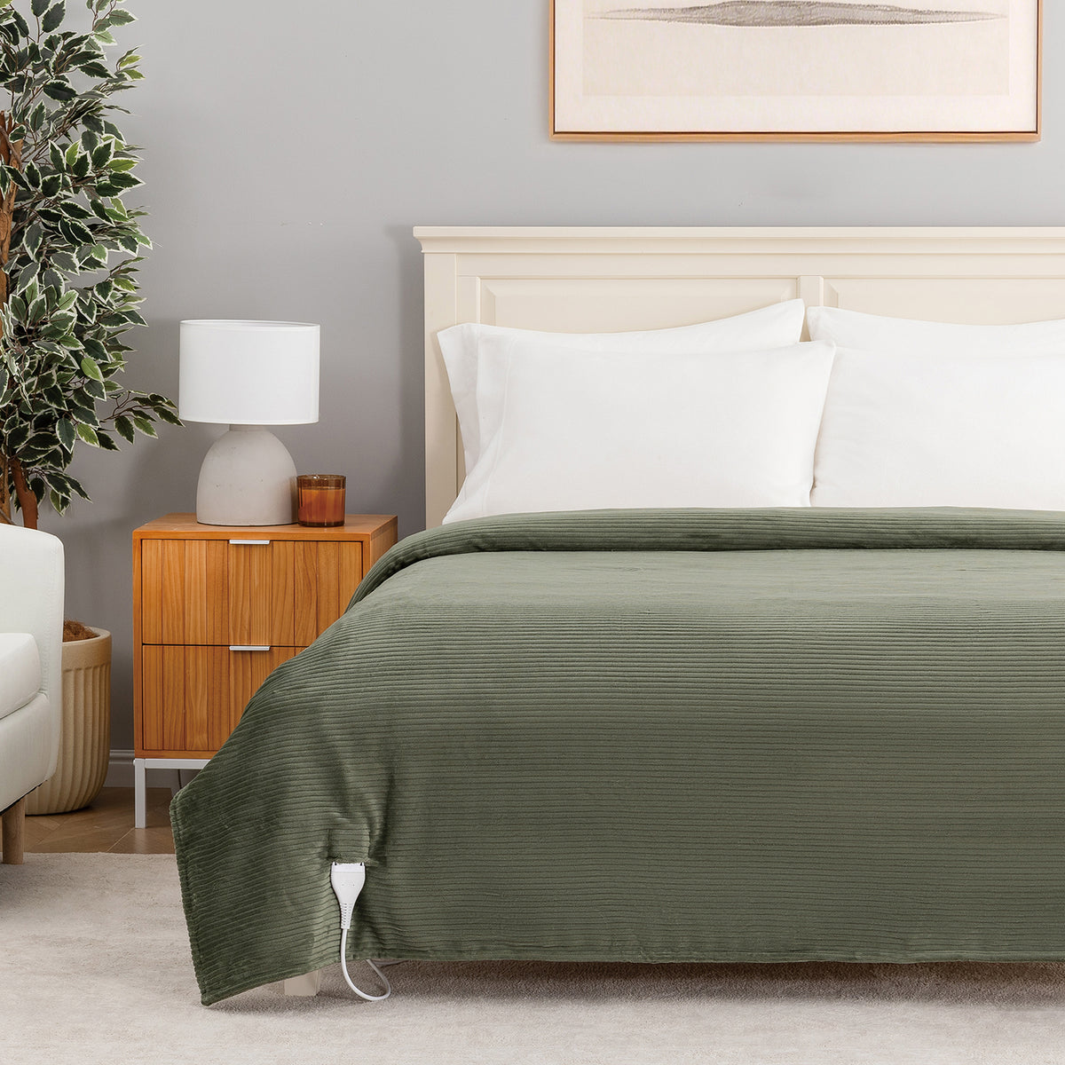An olive green corduroy bedspread with a white control cord, styled on a bed in a modern bedroom setting with a wooden nightstand, lamp, and gray wall.