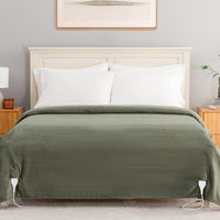 An olive green ribbed blanket or comforter set with white pillows, styled on a bed with a cream headboard in a bedroom setting.