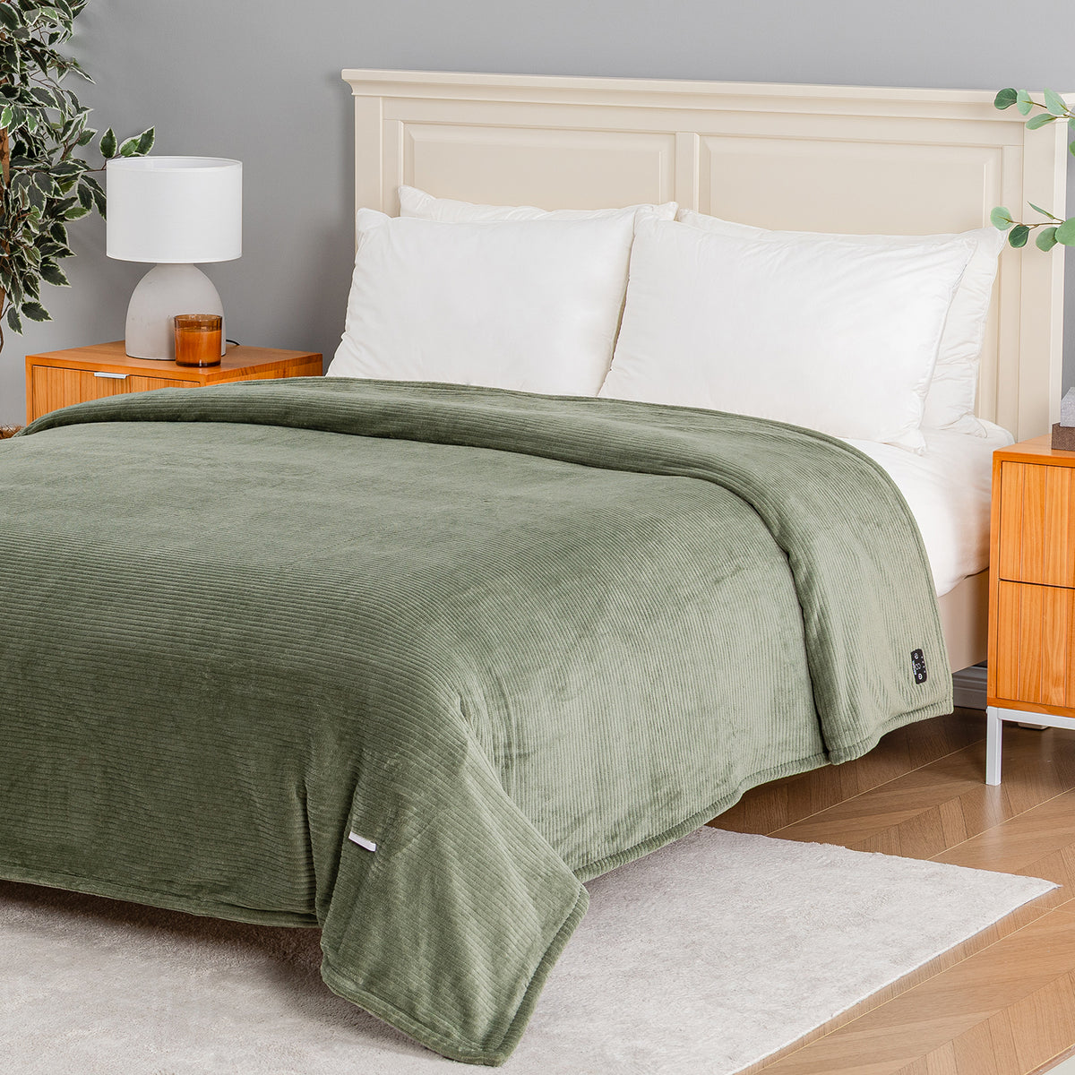 An olive green corduroy blanket is draped over a bed with white pillows and a cream headboard in a modern bedroom setting.