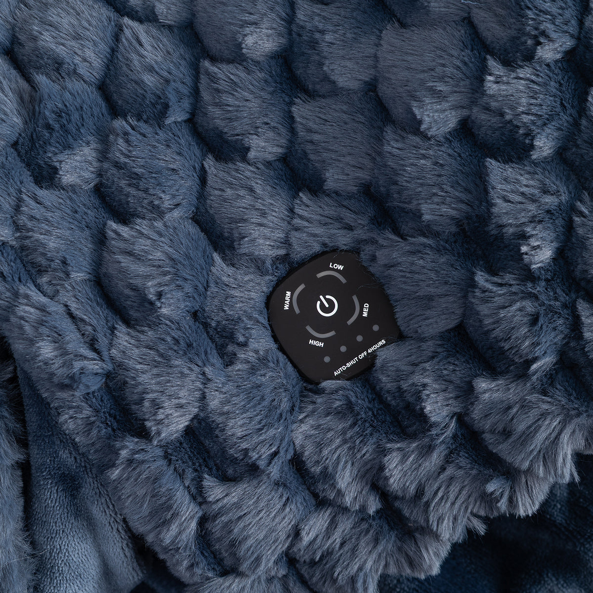 Close-up of a dark blue textured fleece blanket with a black remote control resting on top, showing the remote's power and mode buttons.