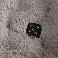 Close-up of a black round control pad with white buttons and labels, embedded in a soft, fluffy gray faux-fur surface.
