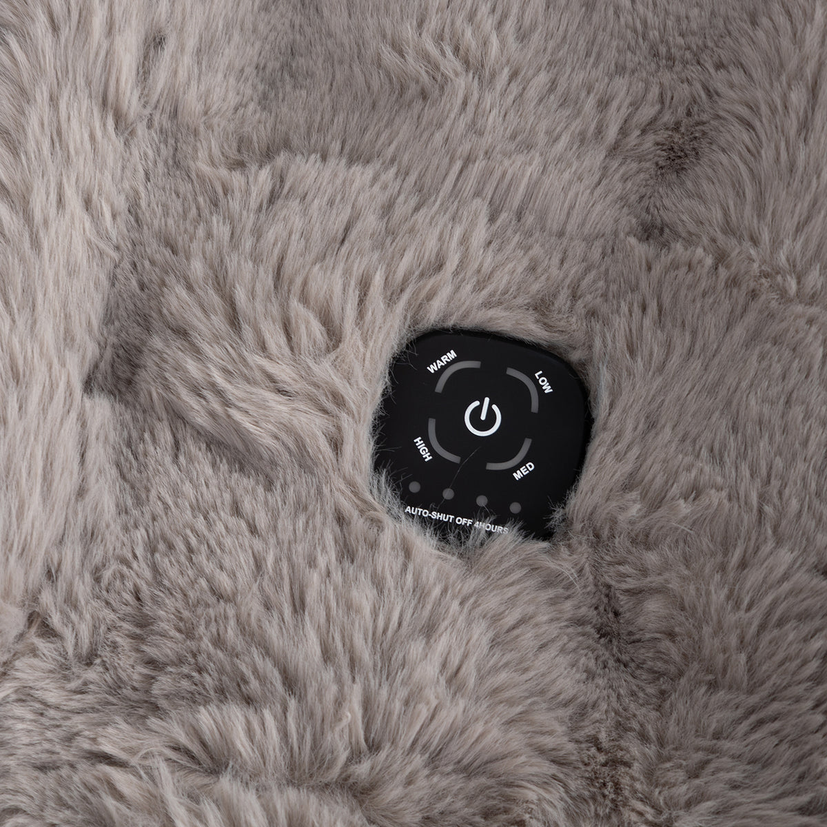 Close-up of a black round control pad with white buttons and labels, embedded in a soft, fluffy gray faux-fur surface.