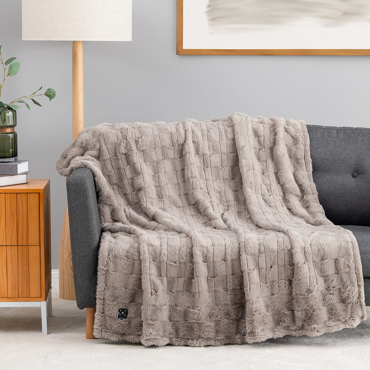 A grey textured faux fur heated throw draped over a chair.