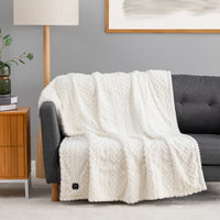 Cream colored faux fur heated throw draped over a chair.