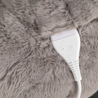 Close-up of a plush gray faux-fur surface with a white power cord and plug inserted.
