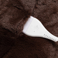 Close-up of a white electronic heating pad or controller placed on a dark brown faux-fur surface.