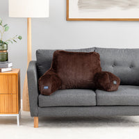 A brown plush lumbar pillow with armrests resting on a gray fabric sofa in a modern living room setting.