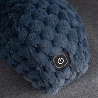 Close-up of a dark blue textured, chunky boucle fabric item with a black power button on a gray fabric surface.
