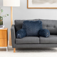 A dark blue quilted lumbar pillow and matching cylindrical bolster pillows displayed on a gray fabric sofa in a modern living room setting.