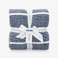 A pair of folded striped knit towels in navy blue and white, tied together with a white ribbon and paper tag from Berkshire Home Furnishings.