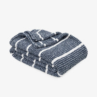 A folded striped knit blanket in navy blue and white, shown on a clean light gray background.